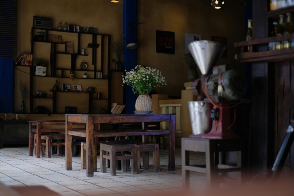 Vintage cafe interior featuring wooden furniture, a vase of white flowers, and rustic decor.